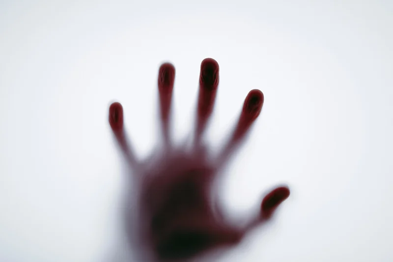 Blurred red hand pressed against frosted glass surface