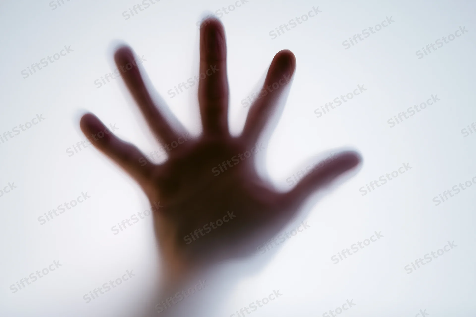 Hand pressed against frosted glass in a closeup view