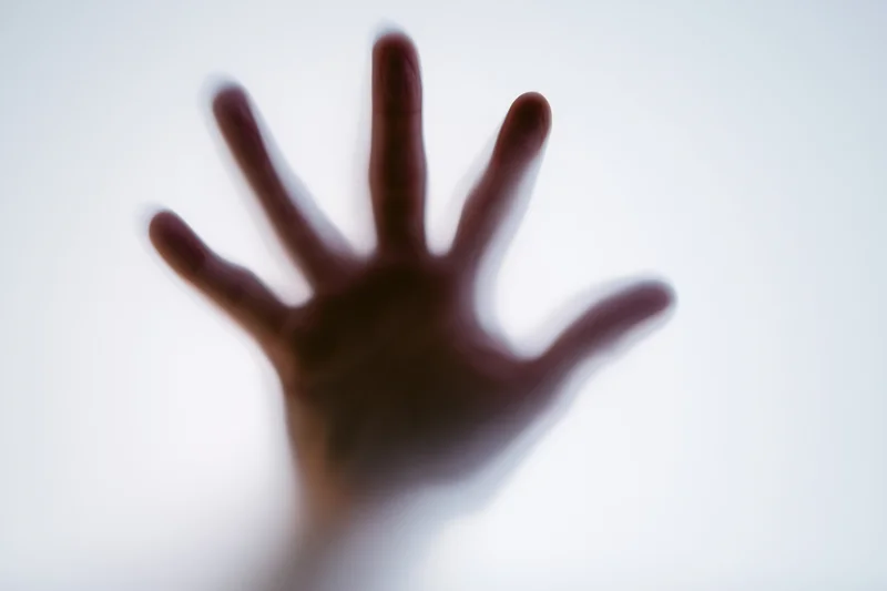 Hand pressed against frosted glass in a closeup view