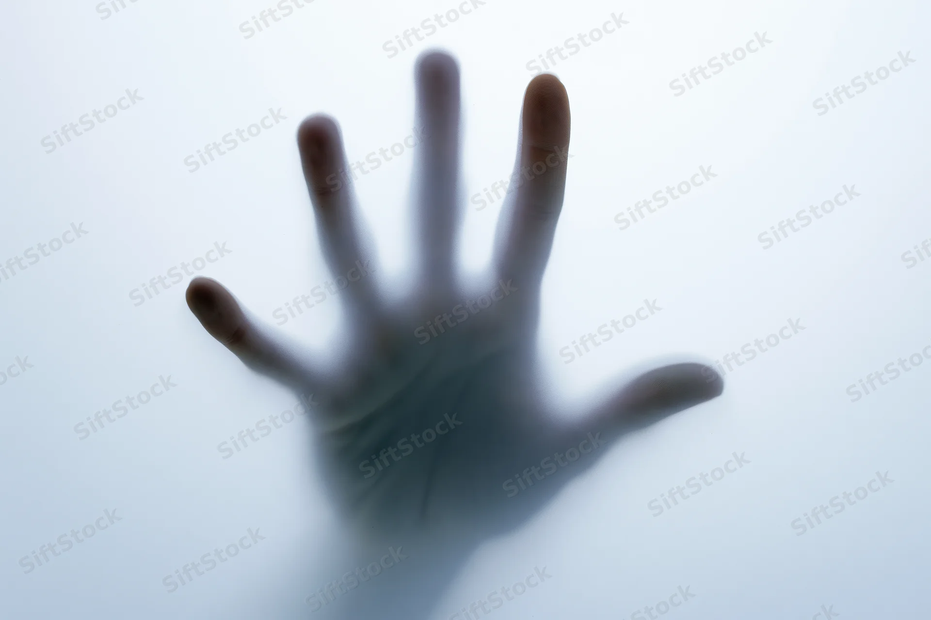 Hand pressing against frosted translucent glass surface