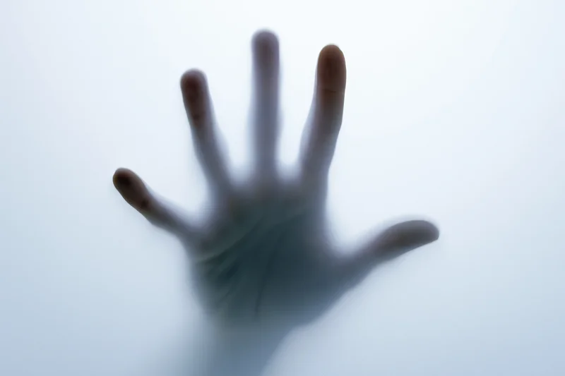 Hand pressing against frosted translucent glass surface