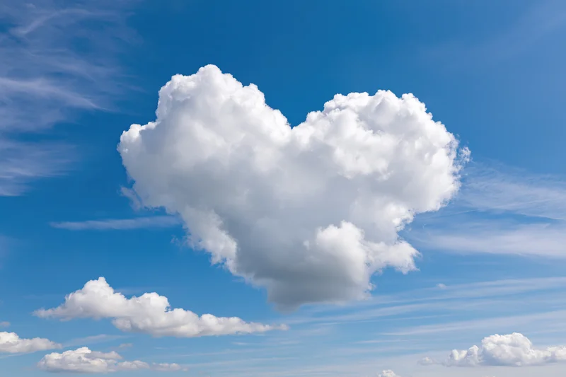 Heart-shaped cloud floating in a clear blue sky