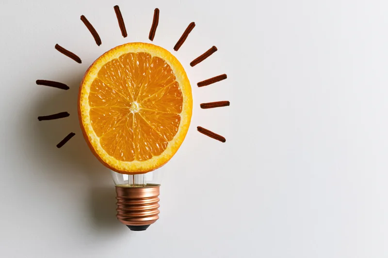 Orange slice replacing glass globe of lightbulb on white background