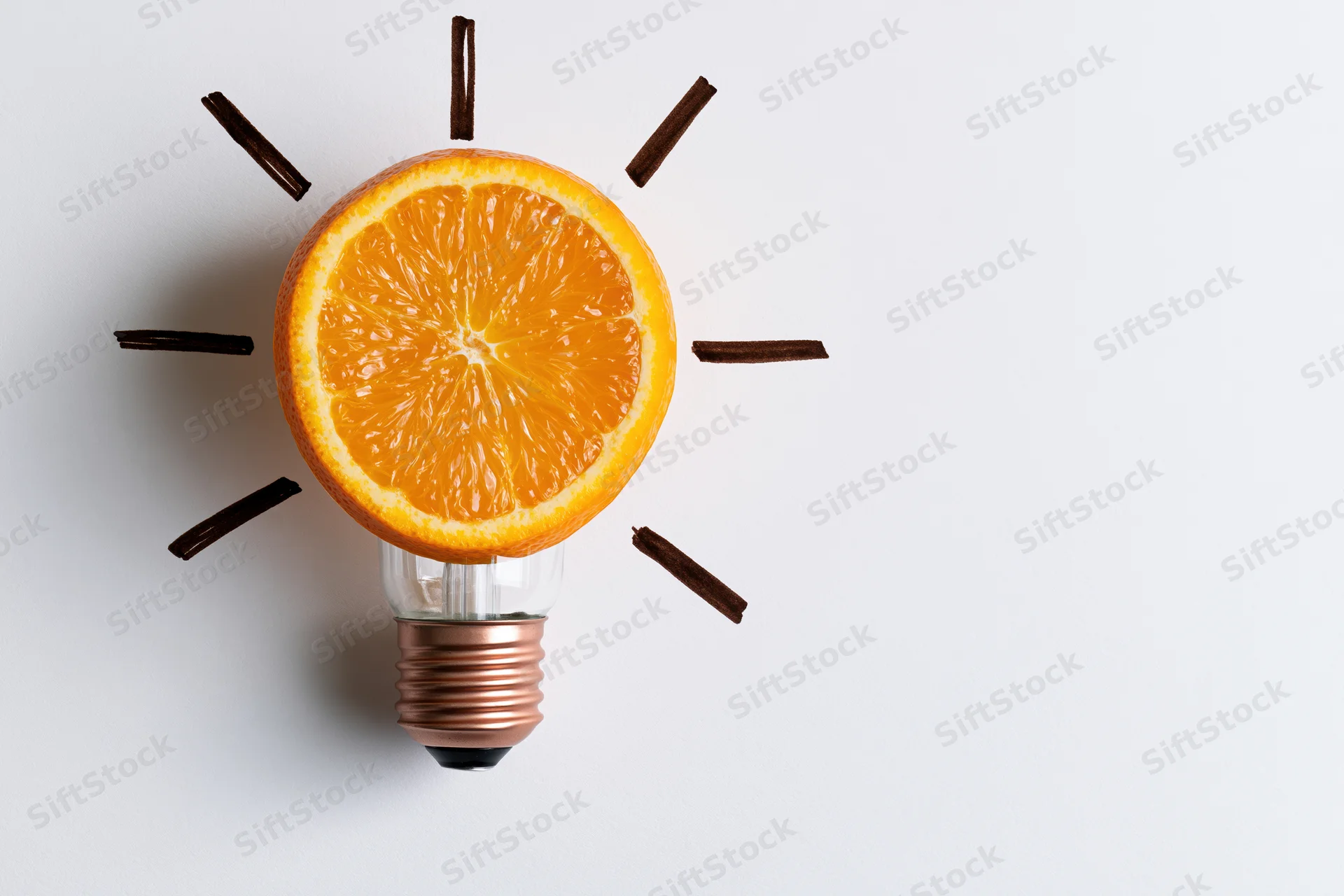 Orange slice replacing glass globe of lightbulb on white surface