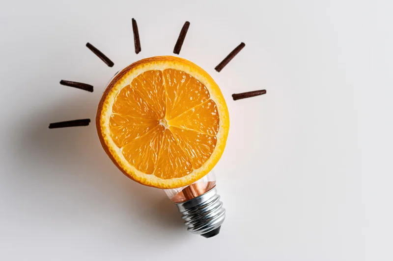Orange slice replacing glass globe of lightbulb on white surface