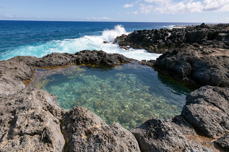 Clear turquoise water in a natural lava rock tidal pool along the ocean coastline