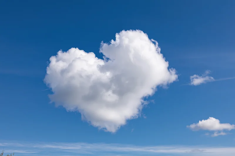 Heart-shaped cloud floating in a clear blue sky