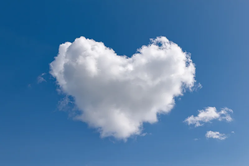 Heart-shaped cloud floating in a clear blue sky
