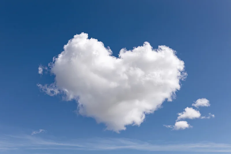 Heart-shaped cloud floating in a clear blue sky