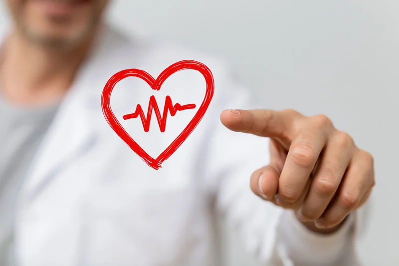 Doctor pointing at a red heart symbol with heartbeat line on a digital interface