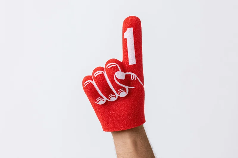 Hand wearing red foam finger with number one raised against white background