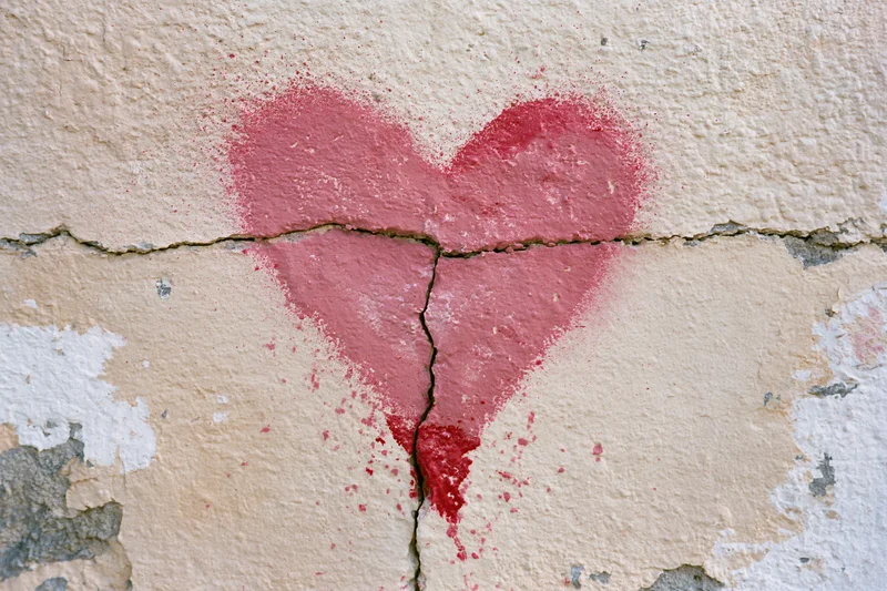 Red spray-painted heart stencil on cracked plaster wall