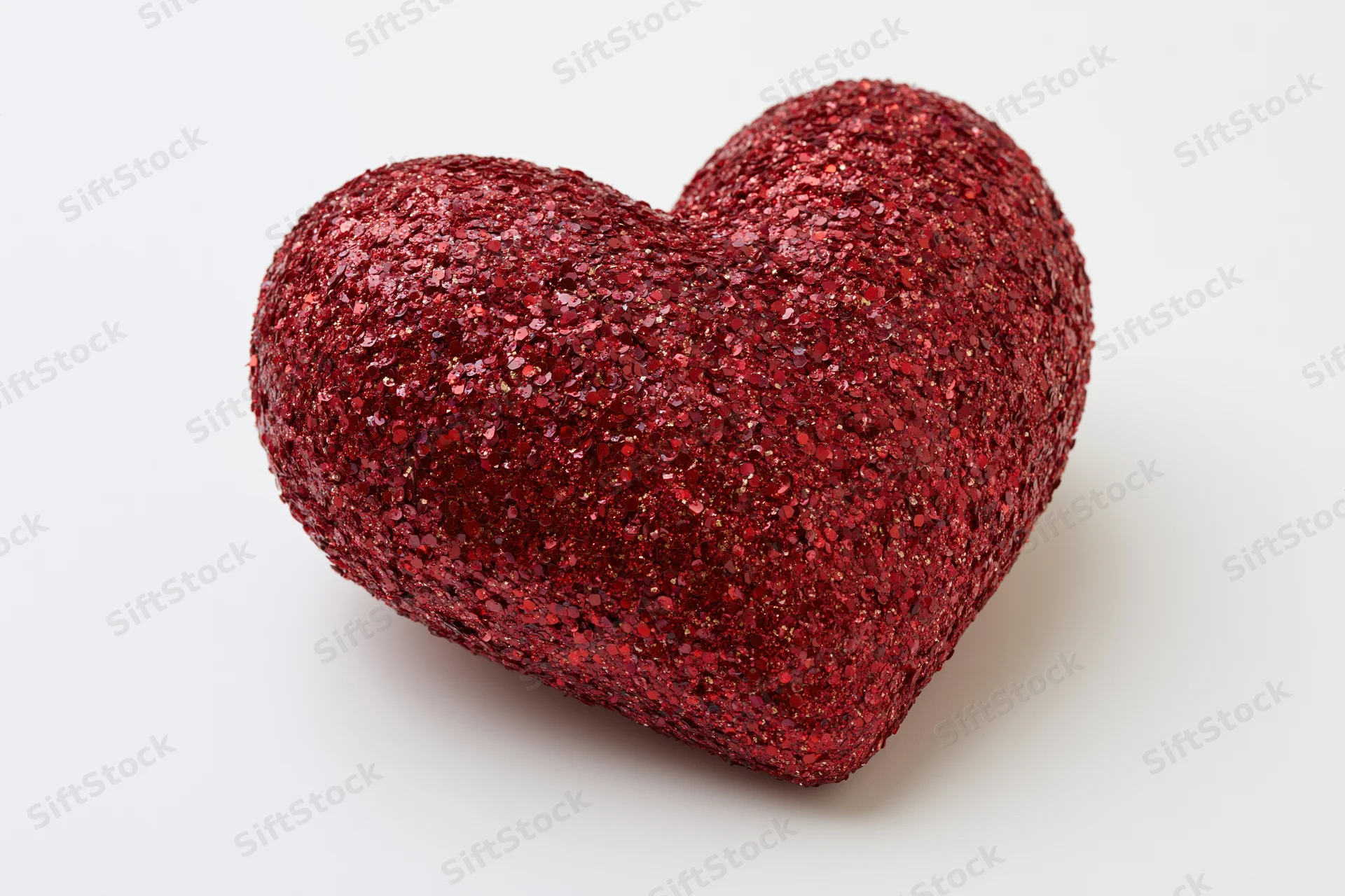 Red glitter heart decoration on white background with copyspace