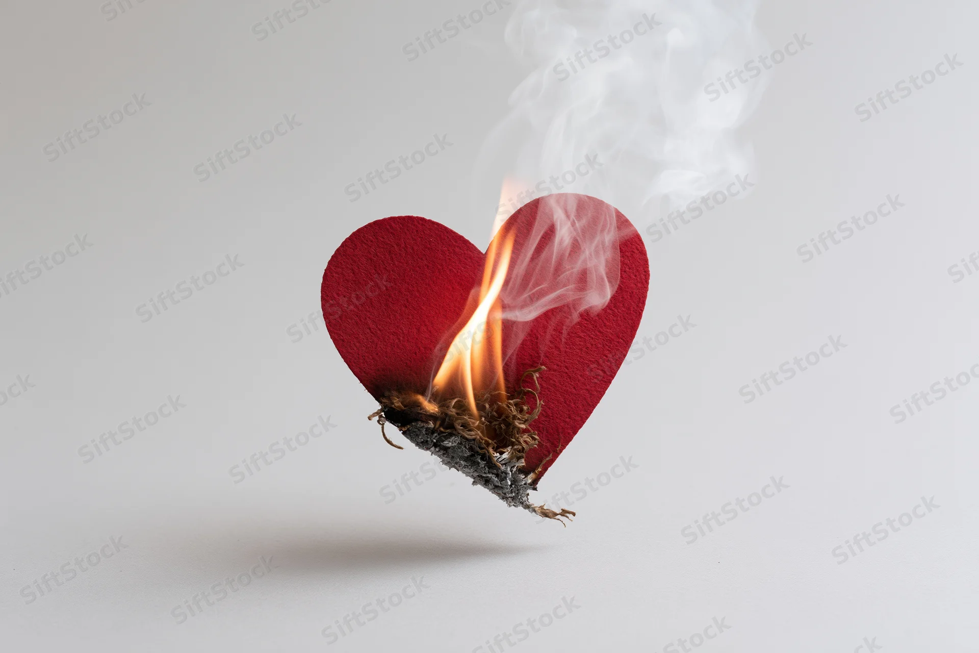 Red felt heart cutout burning with flame and smoke on white background