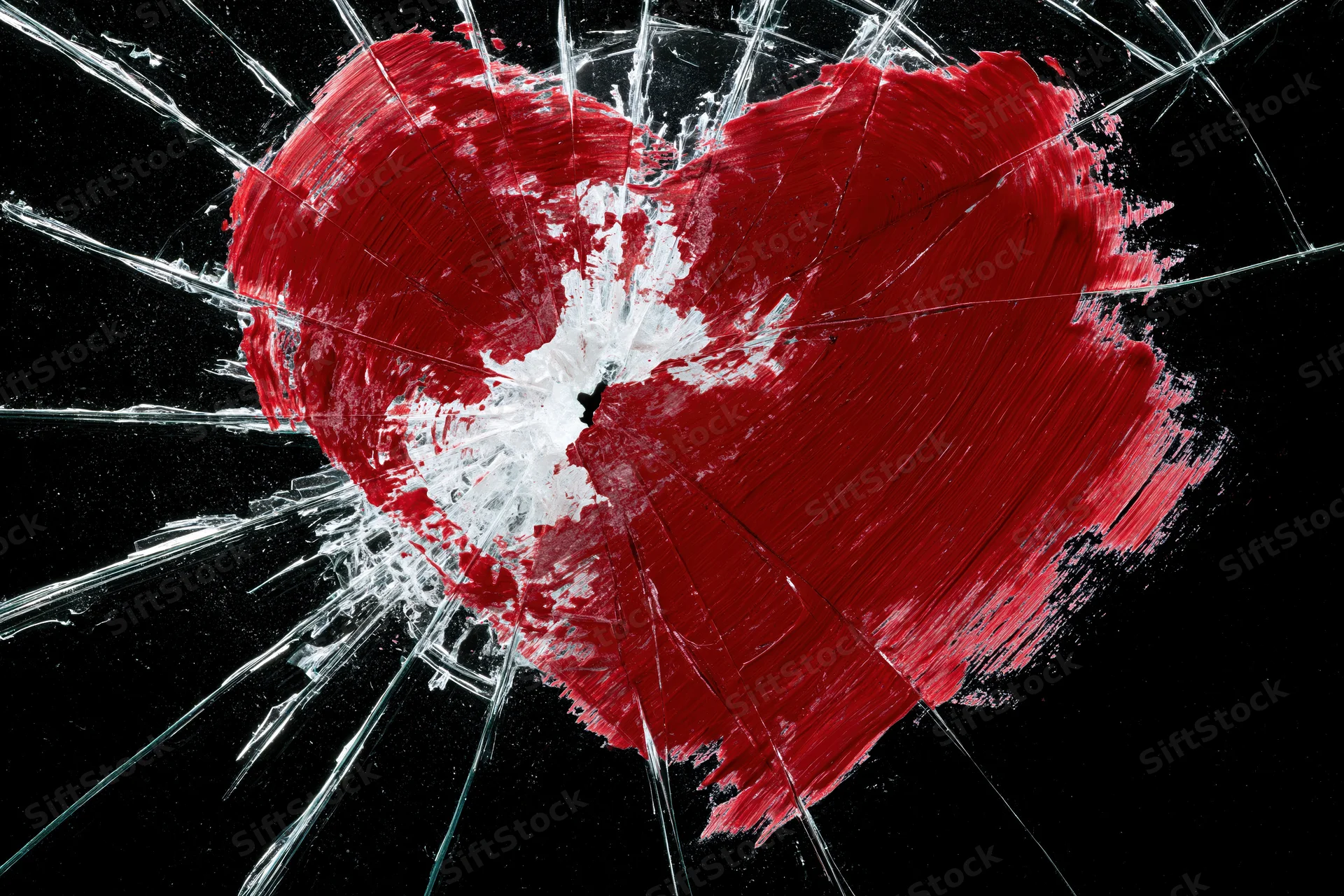 Red painted heart on shattered glass against black background