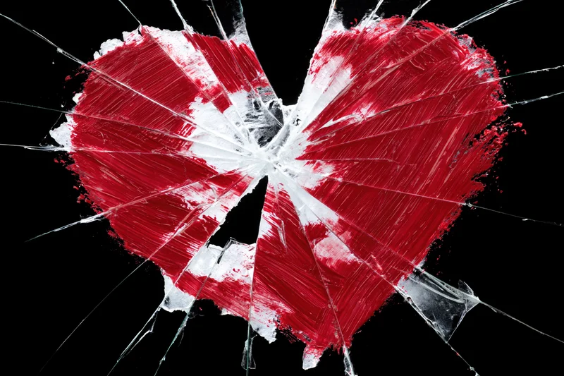 Red heart painted on shattered glass against black background
