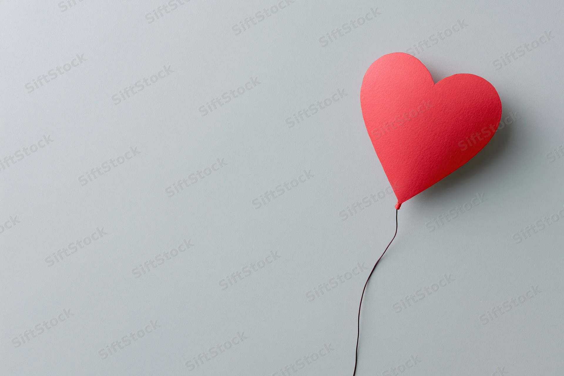 Red paper heart cutout on gray background with copyspace