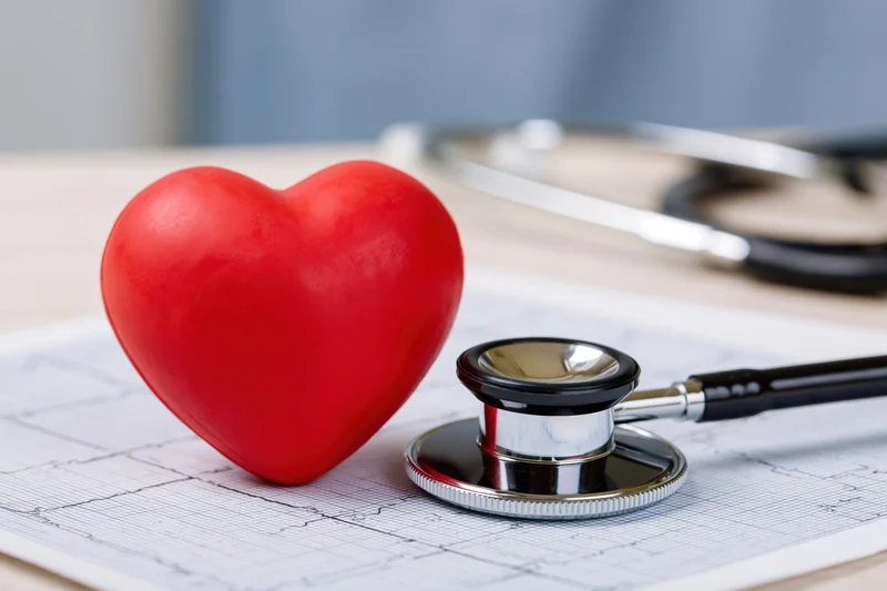 Red heart toy and stethoscope on electrocardiogram paper