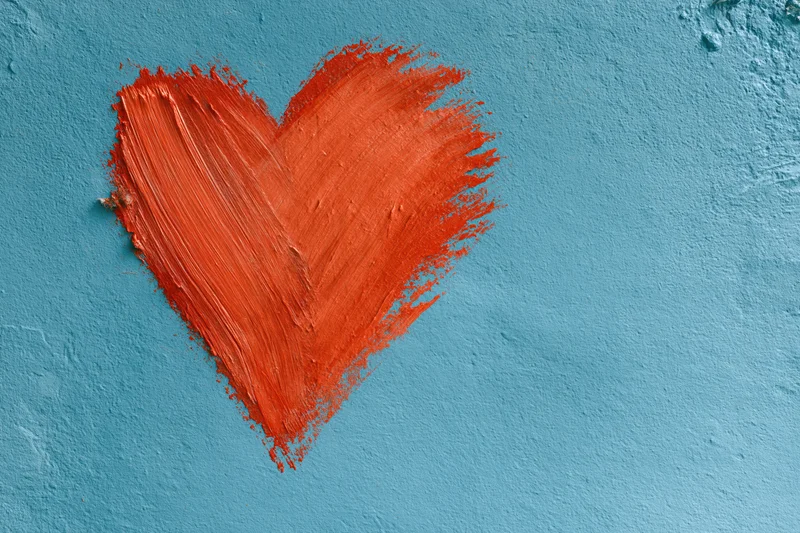 Red painted heart on textured turquoise concrete wall