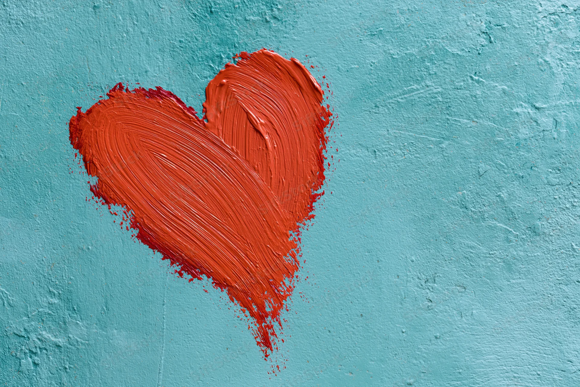 Red painted heart on textured turquoise concrete wall