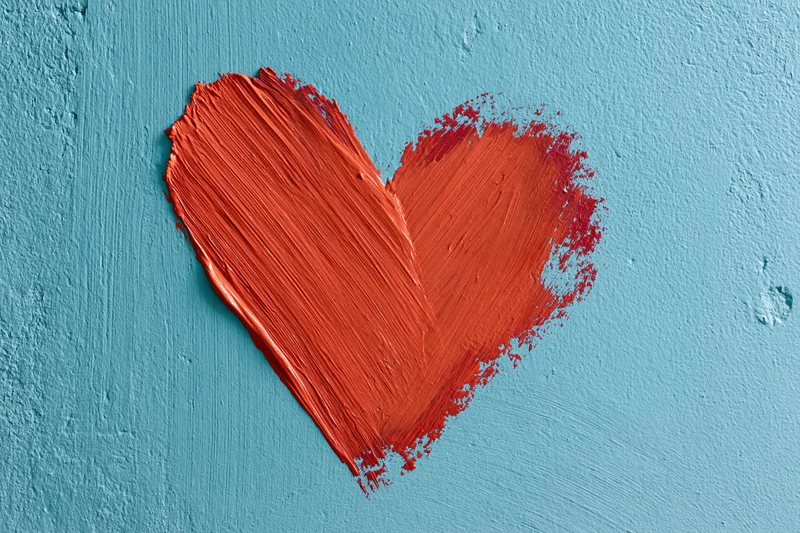 Red painted heart on textured turquoise concrete wall