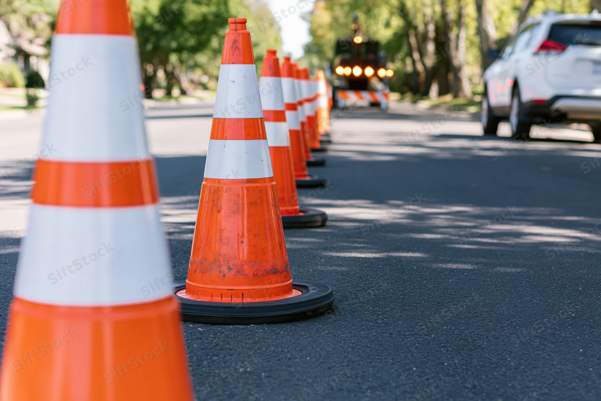 Row of orange traffic cones with white reflective bands lining a street during daytime roadwork