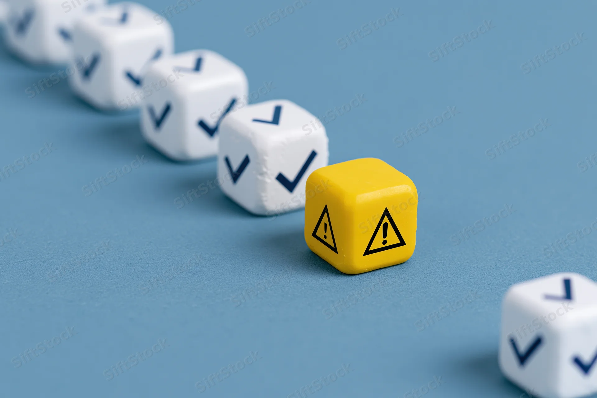Row of white dice with checkmarks and one yellow warning die on blue surface