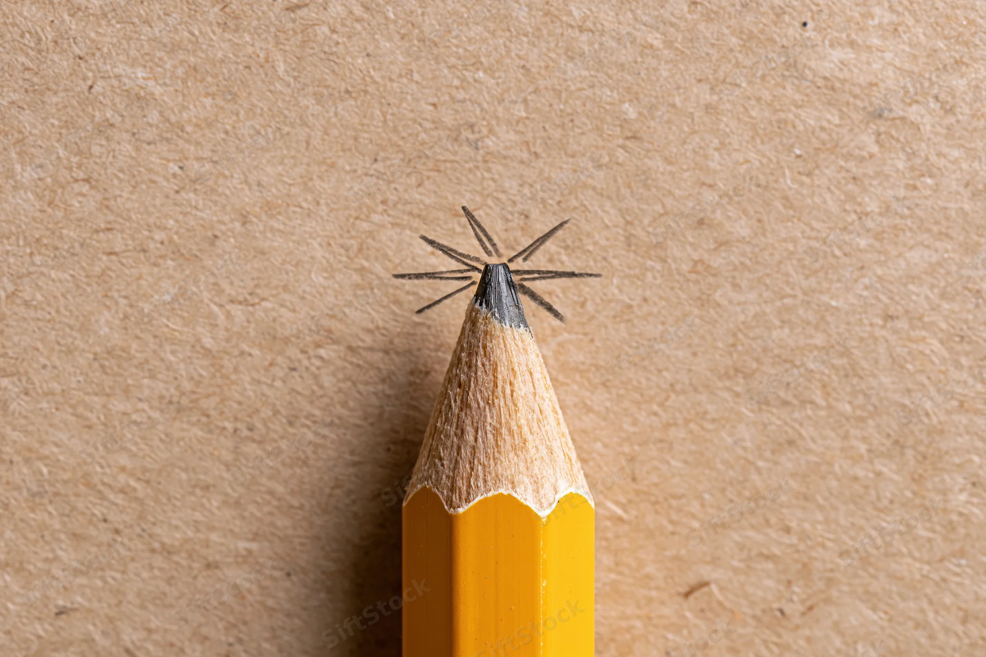 Sharp yellow pencil with hand-drawn star at its tip on textured brown paper