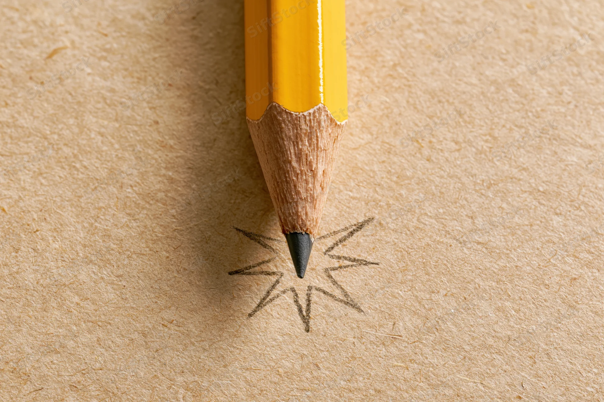 Sharp yellow pencil with hand-drawn starburst on textured paper