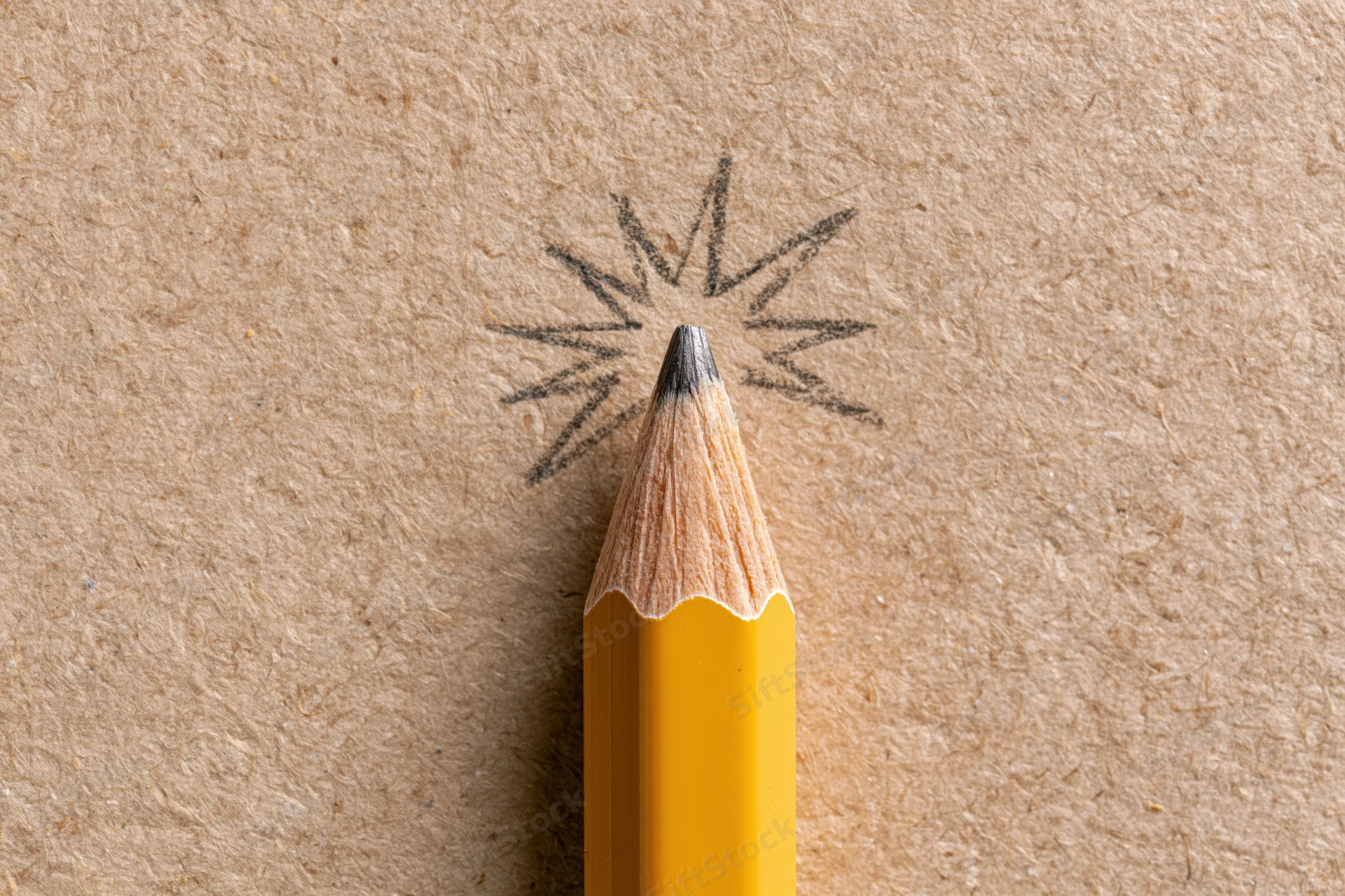Sharp yellow pencil pointing upward with a hand-drawn starburst on textured brown paper