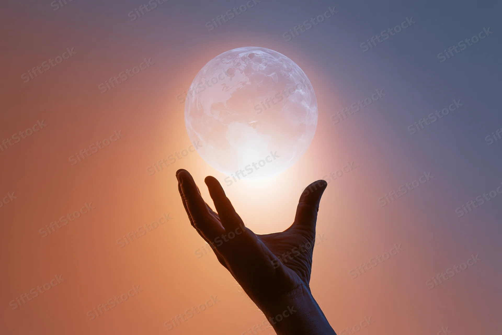 Silhouetted hand reaching toward a glowing moon in a twilight sky