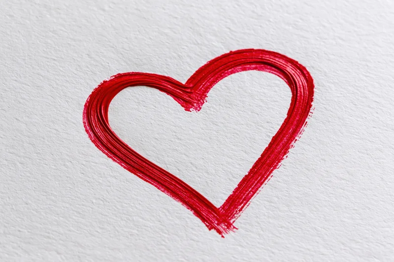 Red heart outline drawn with a single continuous brushstroke on textured white paper