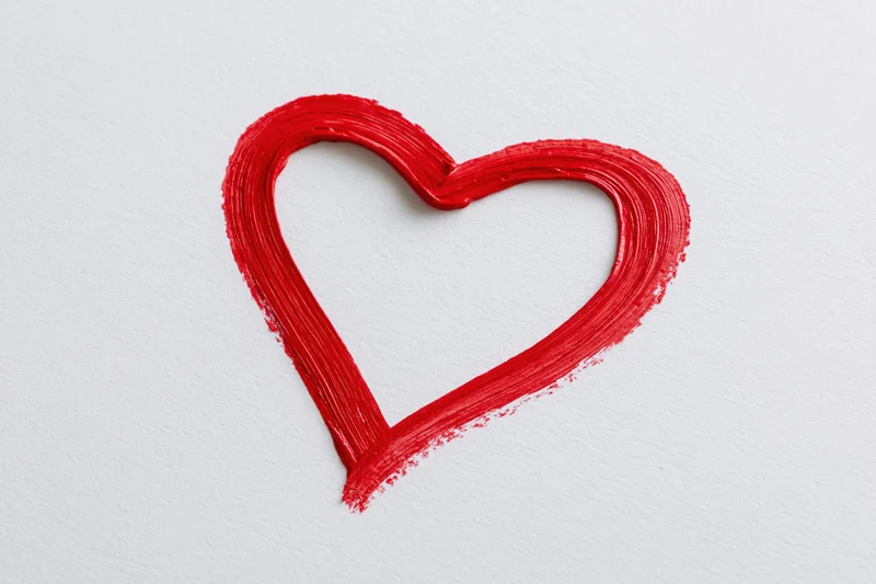 Red heart outline painted with a single continuous brushstroke on white textured paper