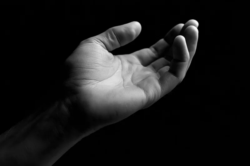 Open hand cupped upward against black background