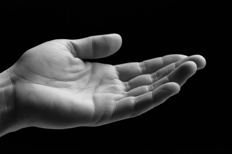 Open hand cupped upward palm facing up against black background