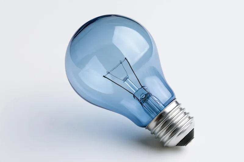 Blue-tinted incandescent light bulb with visible filament on white background