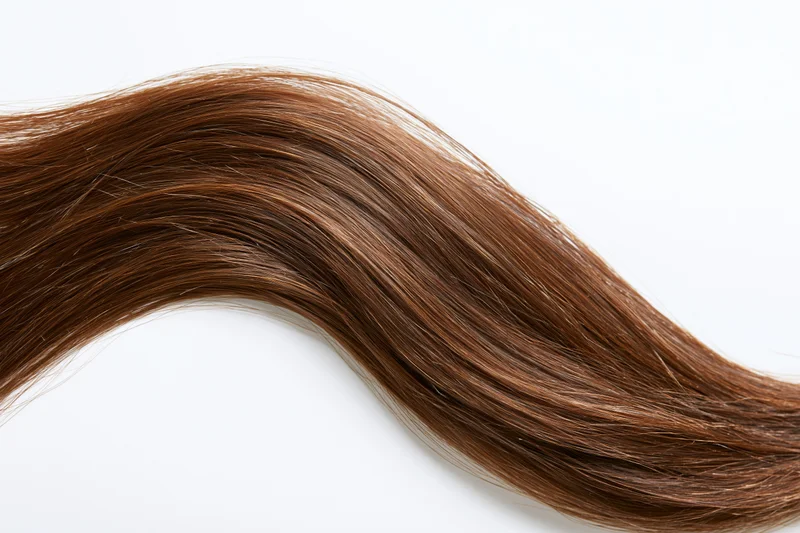 Flowing chestnut brown hair strand on white background