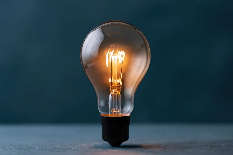 Glowing incandescent lightbulb on a dark surface with soft ambient lighting