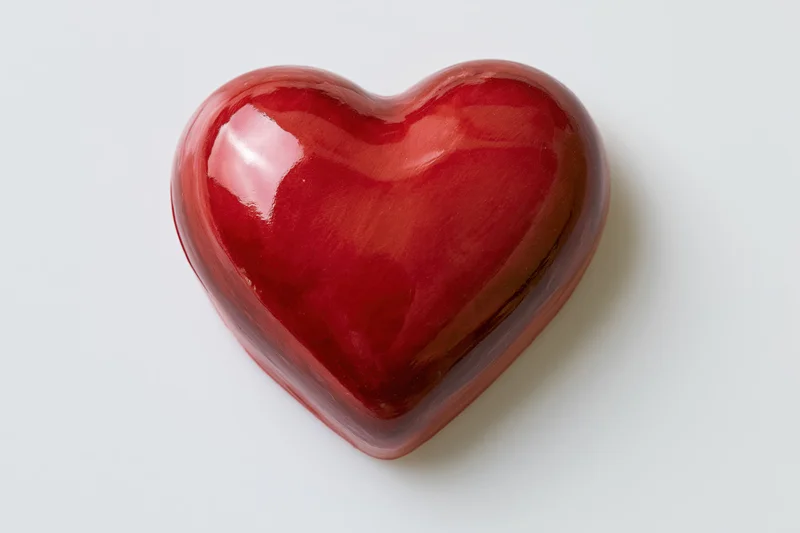 Glossy red heart-shaped candy centered on white background