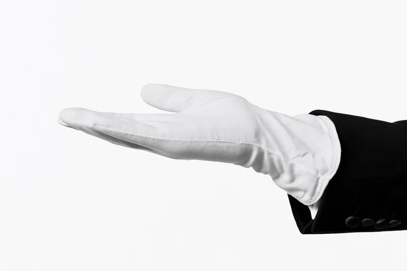 Gloved hand extended palm up in formal suit sleeve against white background