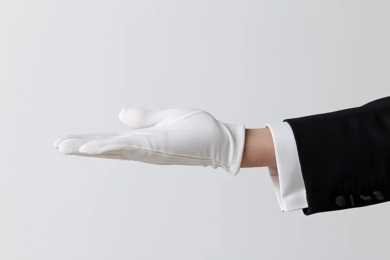 Gloved hand extended palm up in formal attire against white background