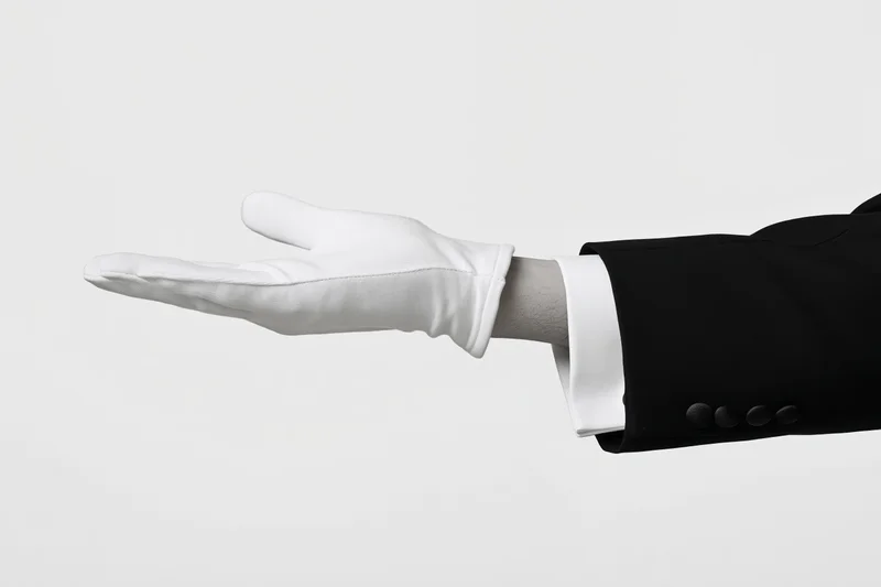 Gloved hand extended palm up in formal suit sleeve against white background