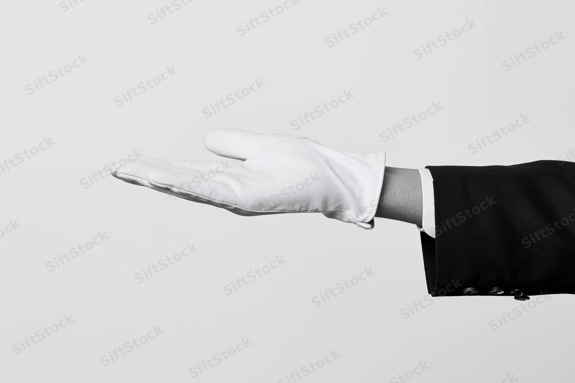 Gloved hand extended palm up in formal suit sleeve against plain background