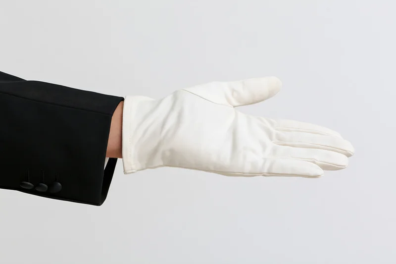 Gloved hand extended palm up in formal attire against white background