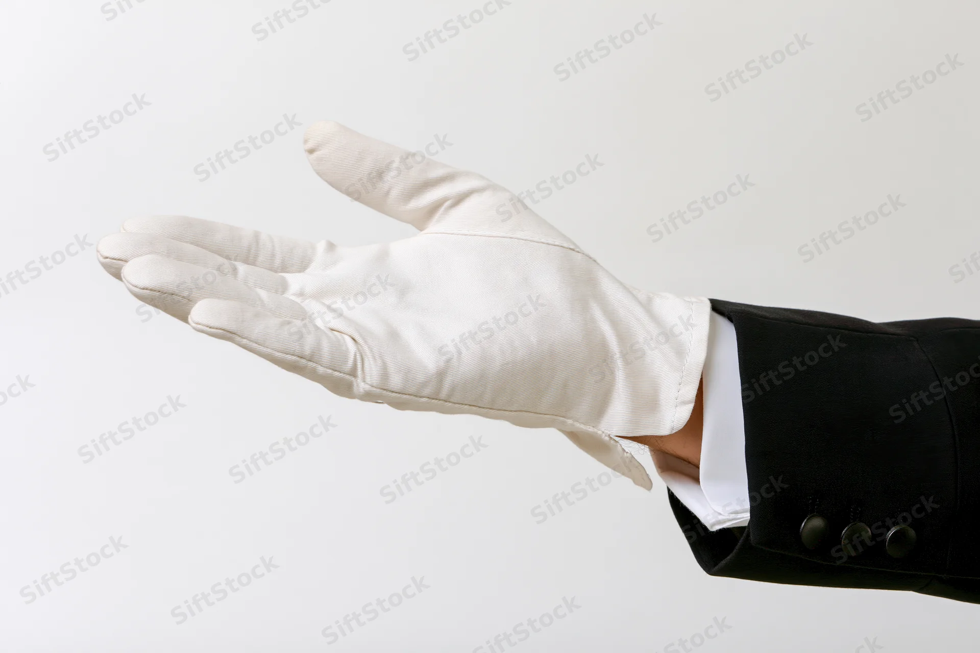 Gloved hand extended palm up in formal suit sleeve against white background