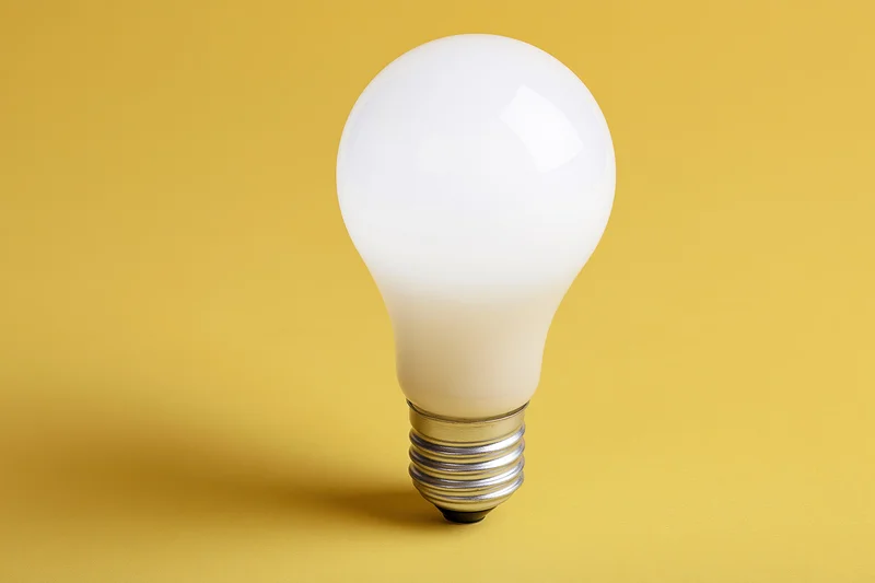 Glowing incandescent light bulb centered on yellow background