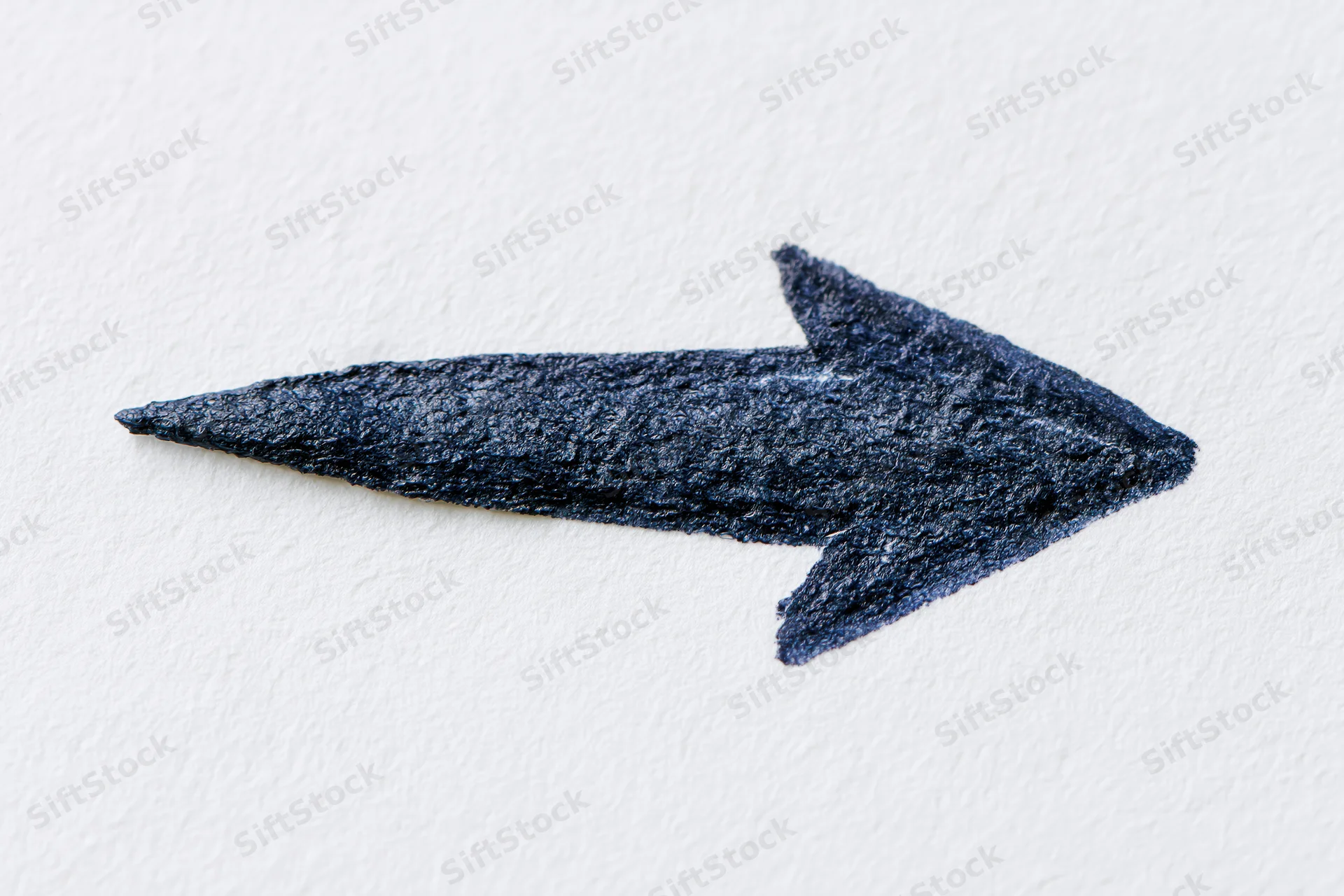 Hand-drawn dark arrow pointing right on white textured paper