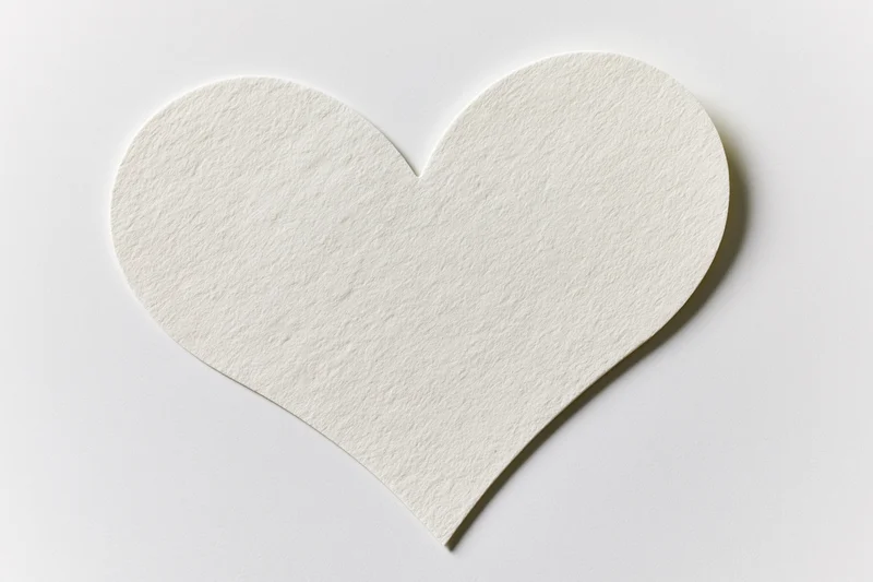 Heart-shaped paper cutout lying flat on white surface