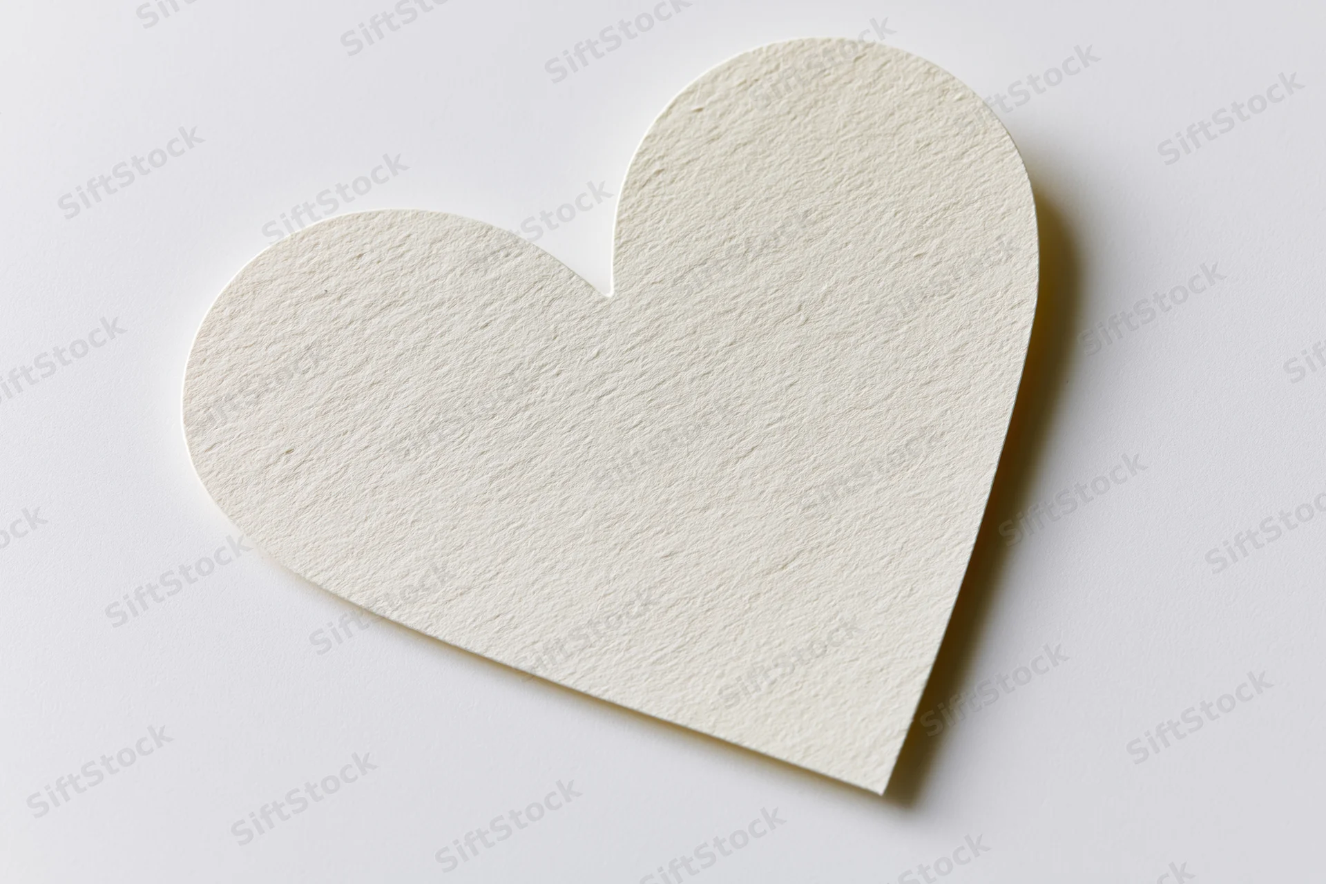 Heart-shaped paper cutout lying flat on white surface