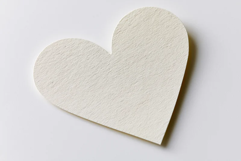 Heart-shaped paper cutout lying flat on white surface